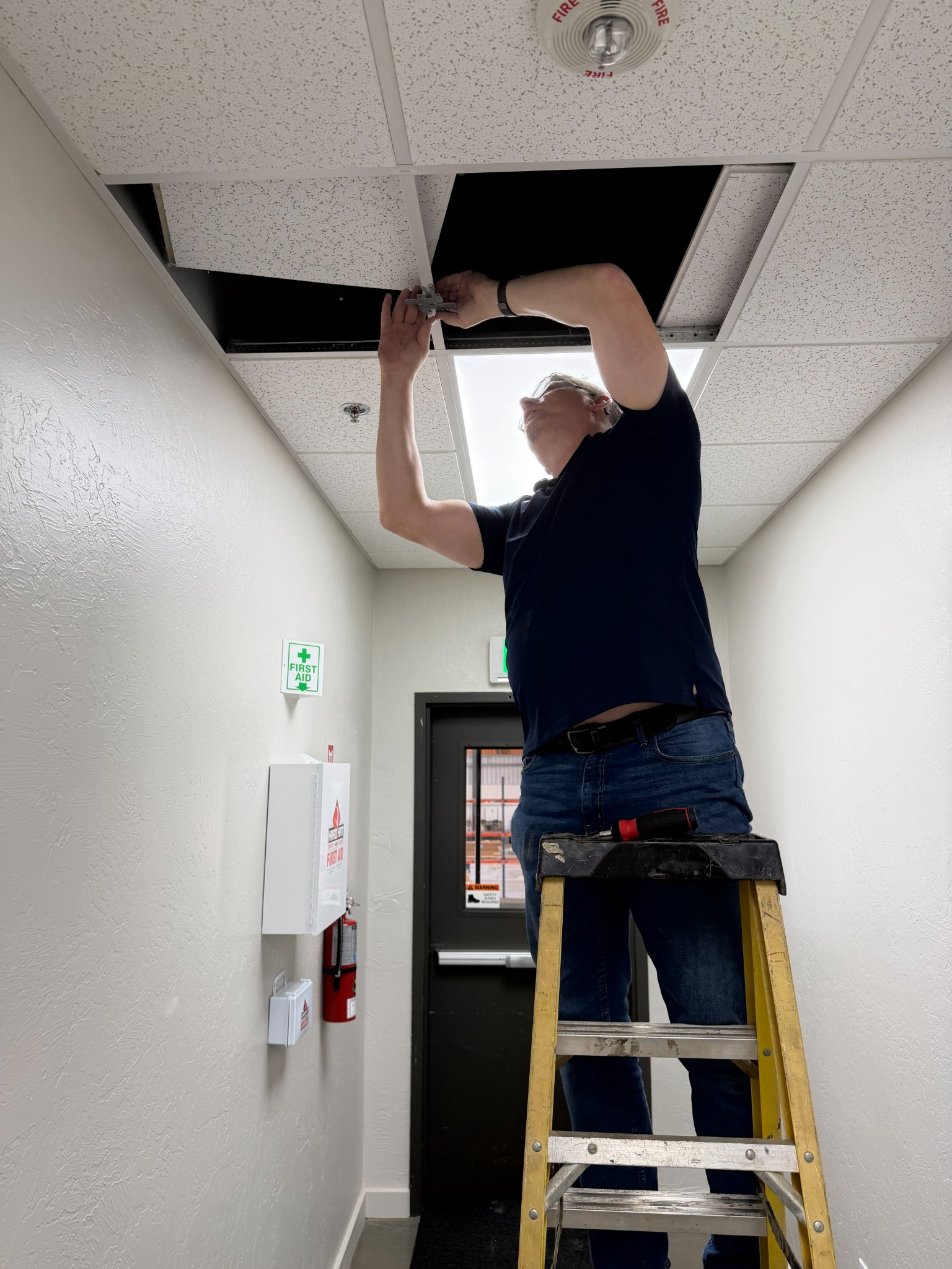 Rivercode technician installing network cabling above a commercial workspace